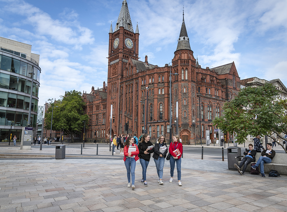 A group of people standing in front of a large red-brick building.